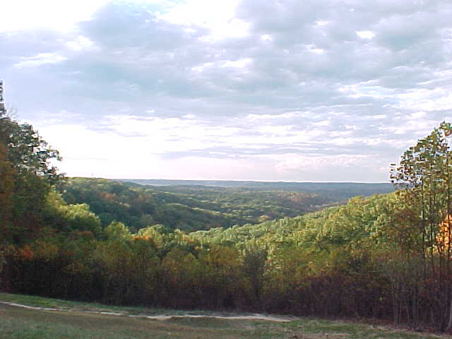 Rollin' tree-covered hills, with rays of sunshine comin' through the hills by the west.